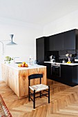 Black kitchen counter and pale, wood-grained island counter in renovated period apartment