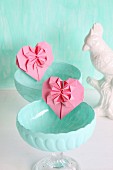 Pink origami hearts in turquoise dessert bowls