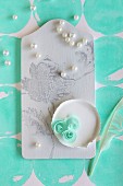 Beads and paper flowers on painted and printed wooden board