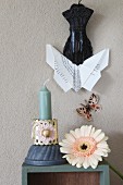 Origami-Schmetterling an einer Klammer über Gerbera und Kerze