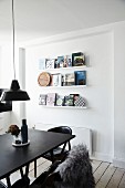 Black dining table in front of books on three narrow shelves