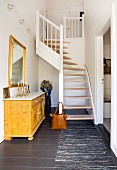 Old chest of drawers and winding modern staircase in hallway