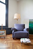 Blue armchair and retro standard lamp on oak parquet floor in period apartment