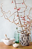 Flowering branches in wicker basket, Italian mortar and pestle, vintage bottles and spice pot