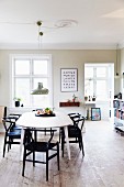 Black designer chairs around oval table in bright dining room