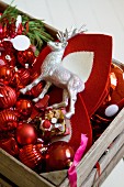 Stag figurine and red Christmas decorations in wooden crate