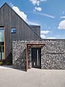 Modernes Haus mit Fassade aus dunklem Holz und Stein