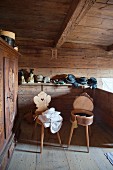 Two old farmhouse chairs in front of traditional hats on shelf