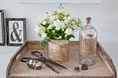 Vase of white roses next to old bottle and vintage ornaments
