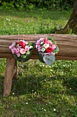 Two metal baskets filled with grass and flowers on wooden bench