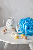 Colourful cake pops and blue pompom on table