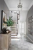 Eleganter Landhaus-Flur mit Holztreppe, Fotogalerie, Kommode und marmoriertem Fliesenboden