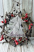 Invitation on wooden tree in wreath of berries