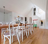 Long wooden dining table with white coffee house chairs