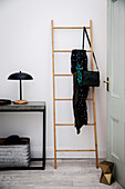 Bamboo ladder leans in the hallway next to a light console table