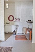 Blick in Bad mit freistehender nostalgischer Badewanne und weißer Mosaikfliesenwand