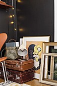 Picture frames and stacked vintage suitcases against black wall
