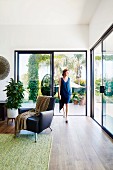 Elegant living area with black leather armchair and patio glazing, woman in front of sliding patio door