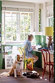 Frau am Laptop in hellem Home-Office mit Hund