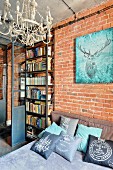 Picture of stag on brick wall above bed with many scatter cushions