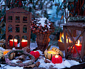 Winter-Stillleben mit roten Kerzen, Eisenlaternen, Hagebutten
