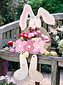 Wood rabbit sitting on wooden bench planted with bellis