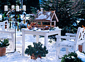 Birdhouse, white wooden furniture, metal stand with Advent wreath, birdseed