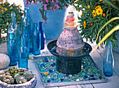 Kleiner Keramikbrunnen auf Blechtablett mit Glassteinen