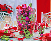 Roter und pinker Baumschmuck in großer Glasvase, grüne Filzanhänger