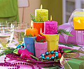 Four colorful candles in colorful coffee cups on pink