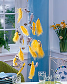Hanging table decoration with yellow and patterned feathers