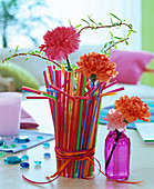Carnations in glass with colorful straws