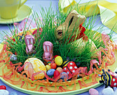 Easter basket with grass, chocolate bunnies, easter and sugar eggs, ladybirds