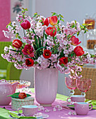 Bouquet with pink Prunus, red tulipa in pink vase