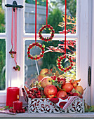 Wreaths of malus hung in the window, basket of apples