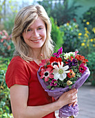 Young woman with bouquet of anemone coronaria (crown anemone)
