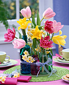 Gesteck aus Tulipa (Tulpen), Narcissus (Narzissen) in kleinen Glasflaschen