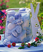 Blue-white easter eggs and feathers in glass vase, malus branch