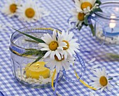 Leucanthemum and grasses on jar with yellow candle