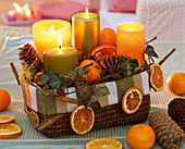 Gesteck mit Citrus (Orangen, Orangenscheiben), Abies (Tannenzapfen), Hedera