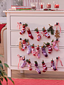 Advent calendar made of small socks hung on drawer chest