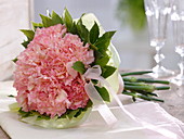 Strauß aus rosa Dianthus (Nelken) mit Laurus (Lorbeer) als Manschette