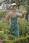 Scarecrow made of straw with gardener's apron in the cottage garden