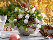 Herbstlicher Strauß aus Rosen, Efeu und Hagebutten in silberner Vase