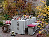 Autumnally decorated table with heather, bouquet of roses and chrysanthemum wreaths