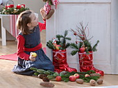 Girl next to red St. Nicholas boots, filled with abies, apples