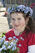 Girl with myosotis (forget-me-not) in pot and as a wreath