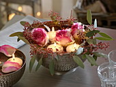 Silver bowl with roses, eucalyptus and, in water floating candles