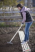 Woman using a rake in the spring to prepare the soil