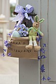 Printed paper bag Lara's Easter basket with purple bow hung on door handle